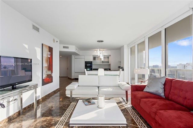 living room with dark tile flooring, a notable chandelier, and floor to ceiling windows