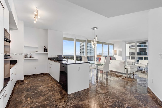 kitchen with kitchen peninsula, rail lighting, dark tile flooring, hanging light fixtures, and dishwasher