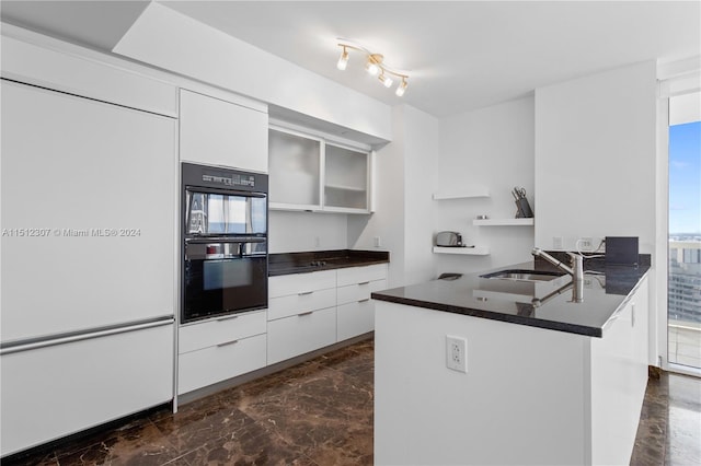 kitchen with white cabinets, double oven, kitchen peninsula, and a wealth of natural light