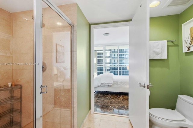 bathroom with tile flooring, a shower with shower door, and toilet