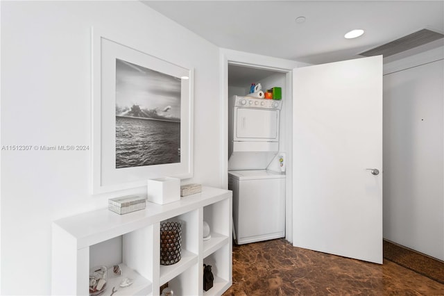 laundry area with stacked washer / dryer and dark tile floors