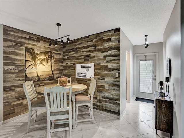 dining area with wood walls, light tile patterned floors, and a textured ceiling