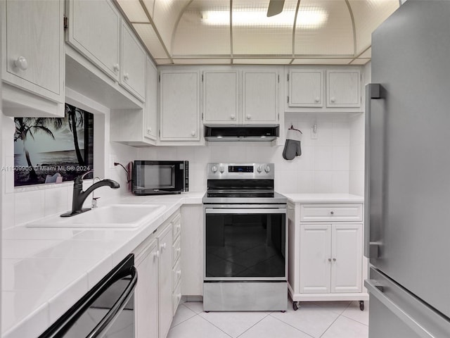 kitchen featuring tile counters, stainless steel appliances, sink, decorative backsplash, and light tile patterned flooring