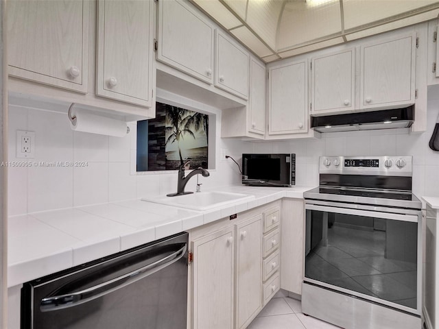 kitchen with backsplash, appliances with stainless steel finishes, tile counters, and sink