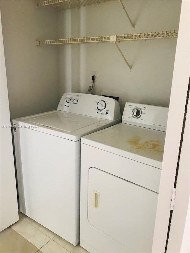 clothes washing area with light tile floors and washer and clothes dryer