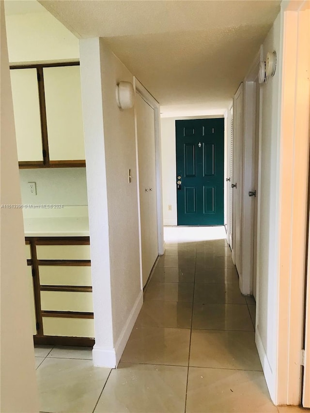 corridor with a textured ceiling and light tile flooring