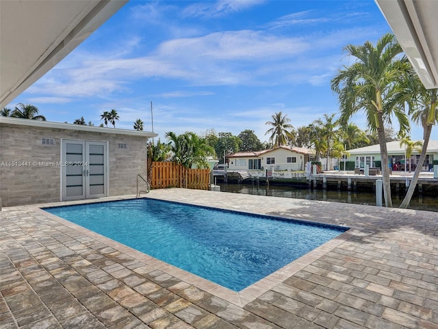 view of swimming pool with a water view, a patio area, and a boat dock