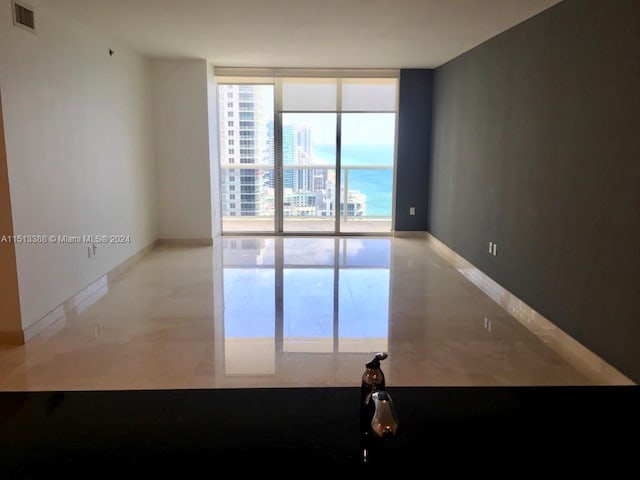 spare room with light tile flooring and a wall of windows