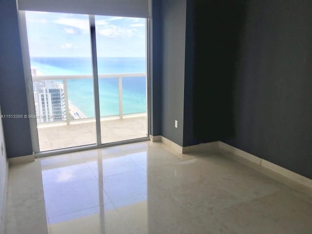 tiled spare room with a water view and expansive windows