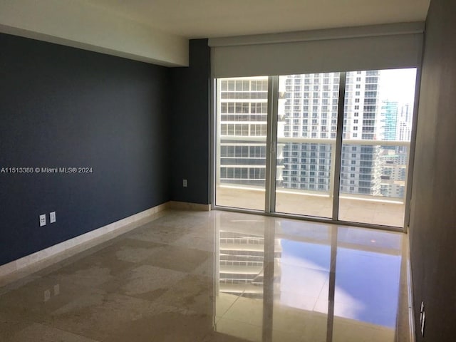 tiled spare room featuring floor to ceiling windows