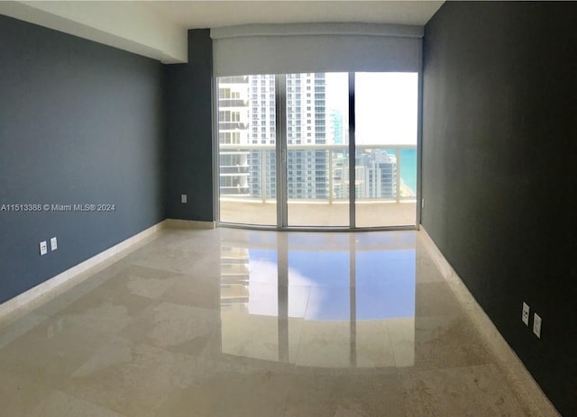 tiled empty room featuring floor to ceiling windows