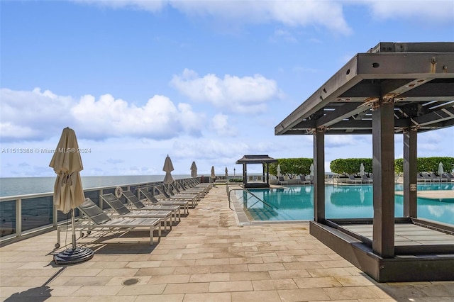 view of swimming pool featuring a water view and a patio area