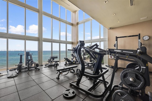 exercise room with a water view and a high ceiling