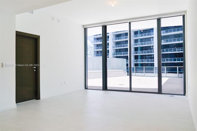 empty room featuring a wall of windows and hardwood / wood-style flooring