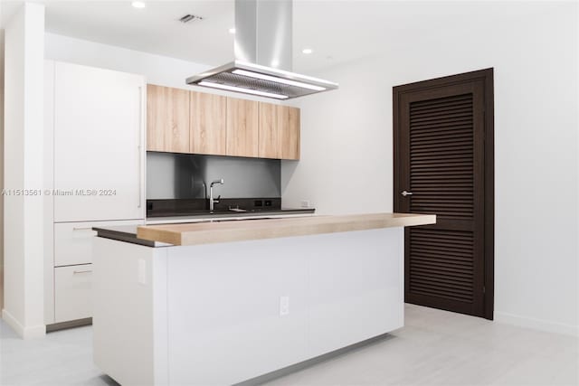 kitchen featuring island exhaust hood, a kitchen island, sink, and white cabinetry