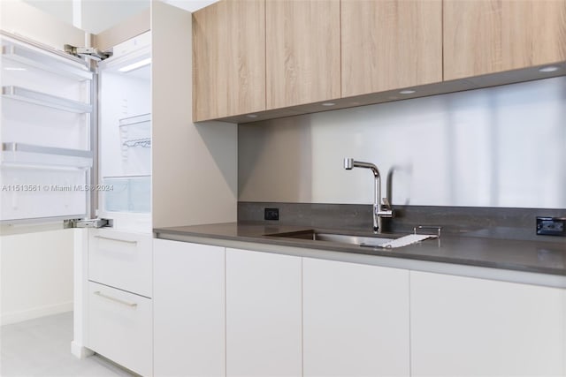 kitchen with white cabinets, light brown cabinets, and sink