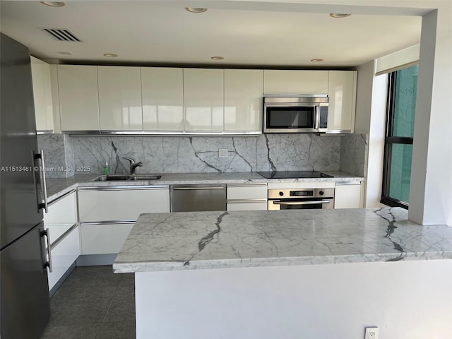 kitchen featuring decorative backsplash, sink, white cabinets, and appliances with stainless steel finishes