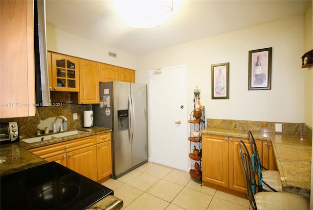 kitchen featuring light tile patterned flooring, sink, backsplash, black appliances, and dark stone counters