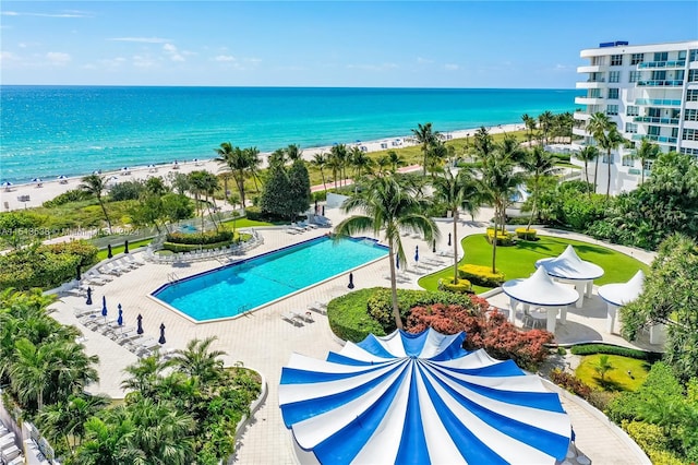 view of swimming pool featuring a patio, a water view, and a beach view