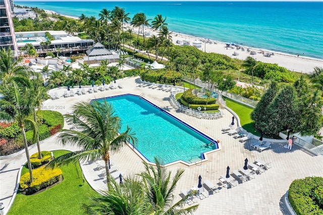 view of swimming pool with a beach view, a patio, and a water view