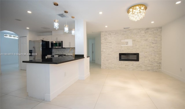 kitchen with light tile flooring, kitchen peninsula, tasteful backsplash, appliances with stainless steel finishes, and white cabinetry