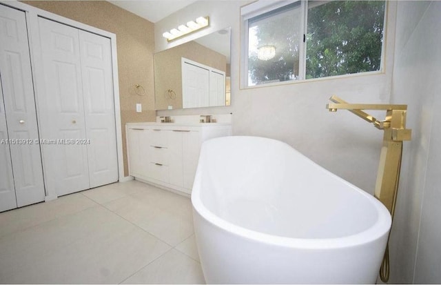 bathroom with tile floors, vanity with extensive cabinet space, and a bathtub