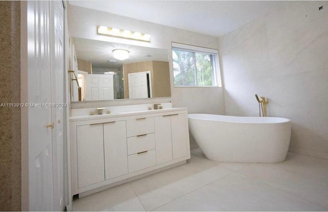 bathroom with tile walls, tile floors, vanity, and a bath to relax in