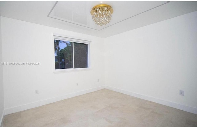 unfurnished room featuring an inviting chandelier and light carpet