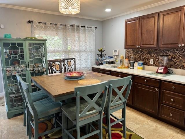 kitchen featuring tasteful backsplash, dark brown cabinetry, ornamental molding, and a kitchen breakfast bar