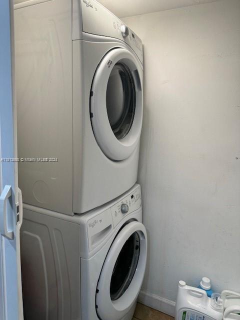 clothes washing area featuring tile patterned floors and stacked washing maching and dryer