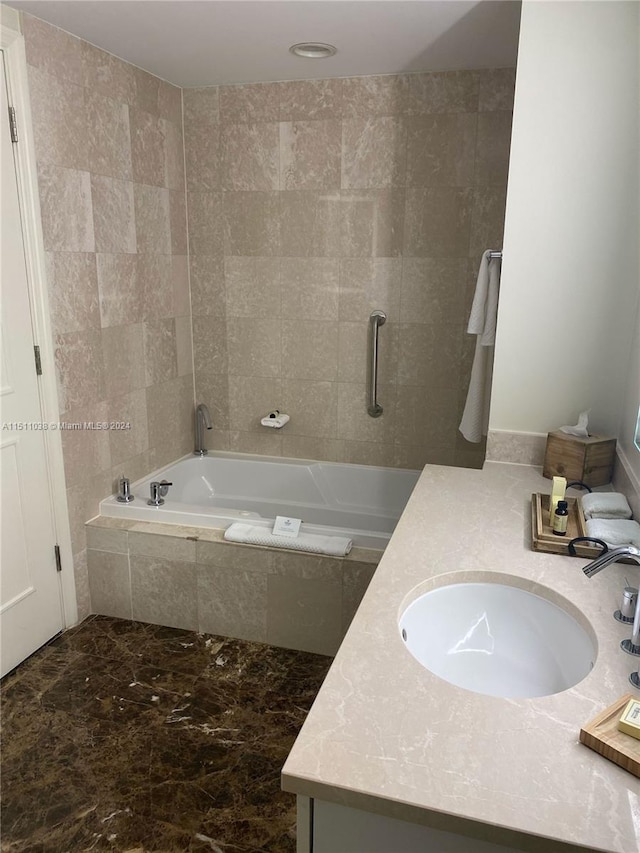 bathroom featuring tiled tub, tile flooring, and vanity