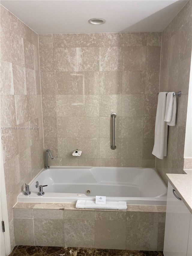 bathroom featuring vanity, tiled tub, and tile walls