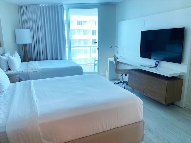 bedroom with light hardwood / wood-style floors and a wall of windows