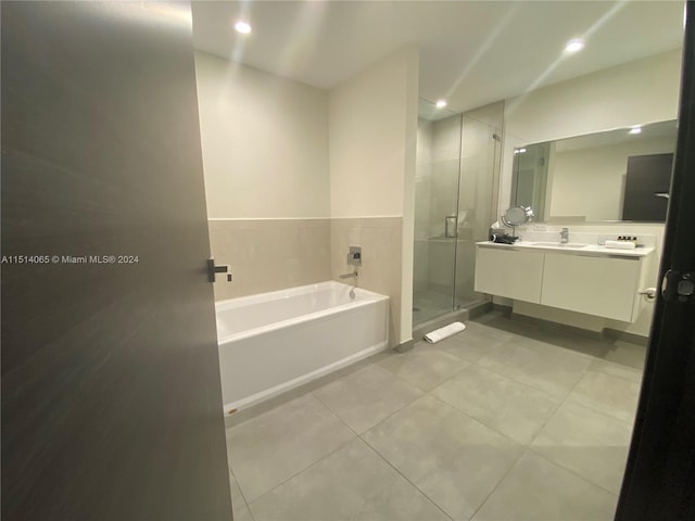 bathroom with separate shower and tub, vanity with extensive cabinet space, and tile flooring