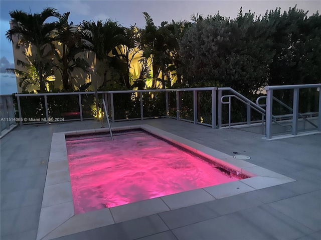 pool at dusk featuring a patio area