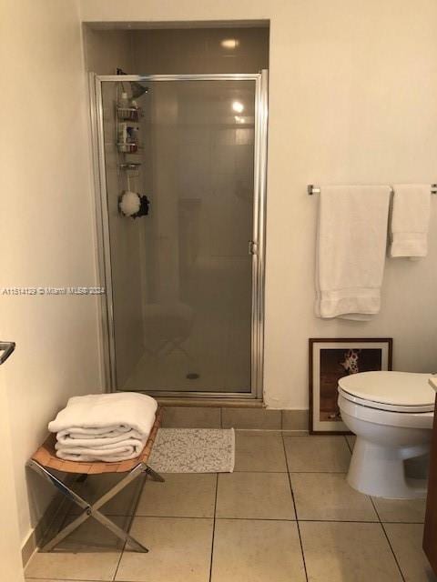 bathroom with tile patterned flooring, toilet, and an enclosed shower