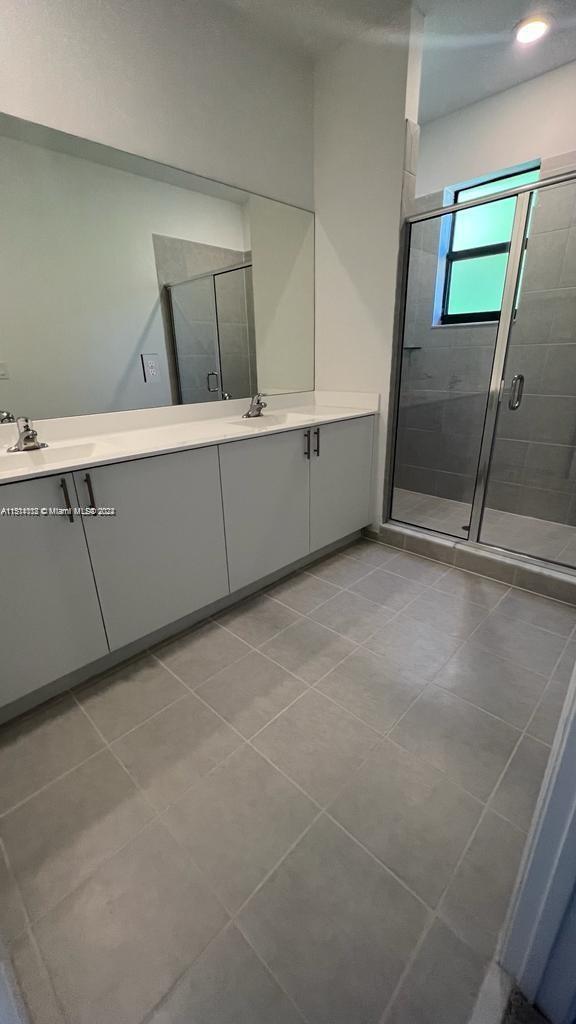 bathroom featuring tile flooring, an enclosed shower, and vanity