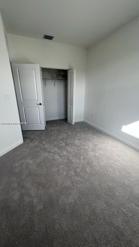 unfurnished bedroom with a closet and dark carpet