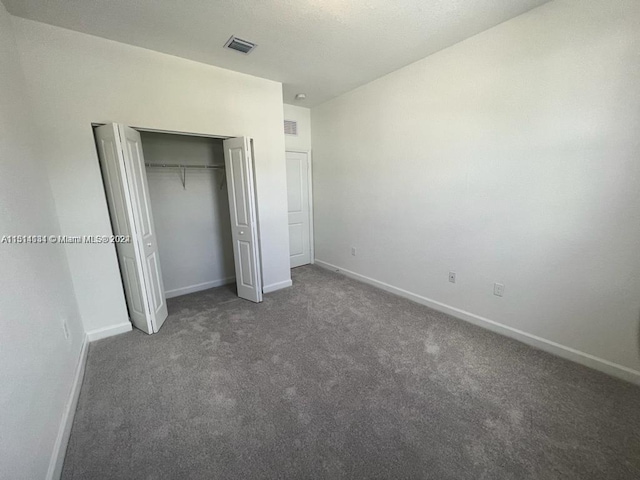 unfurnished bedroom with a closet and dark colored carpet