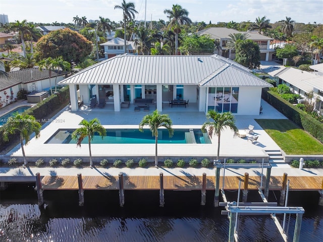 rear view of property featuring a fenced in pool, a patio area, and a water view