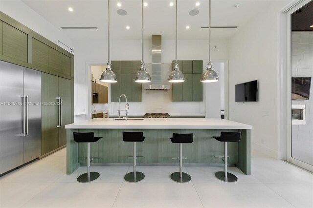 kitchen featuring sink, hanging light fixtures, wall chimney exhaust hood, and a breakfast bar area