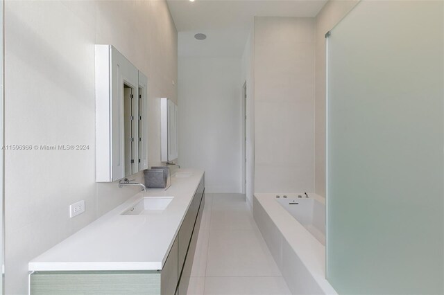 bathroom featuring a relaxing tiled tub, vanity, and tile patterned flooring