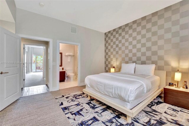 bedroom with connected bathroom and light colored carpet