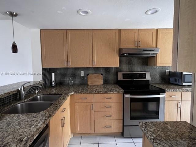 kitchen featuring light tile patterned flooring, sink, dark stone countertops, appliances with stainless steel finishes, and tasteful backsplash