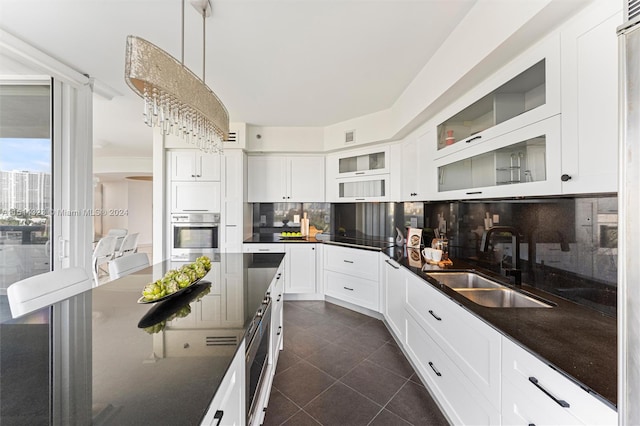 kitchen with hanging light fixtures, wall oven, sink, tasteful backsplash, and dark tile patterned floors