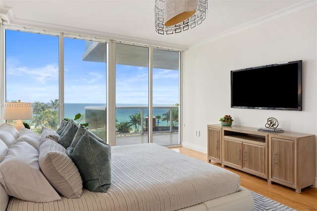 bedroom with access to outside, light hardwood / wood-style flooring, ornamental molding, and expansive windows