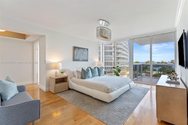 bedroom with floor to ceiling windows, light wood-type flooring, access to outside, and ornamental molding