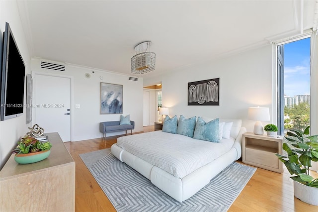 bedroom with ornamental molding and light hardwood / wood-style floors