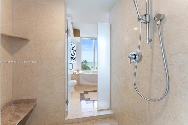 bathroom with a tile shower, tile patterned floors, and toilet