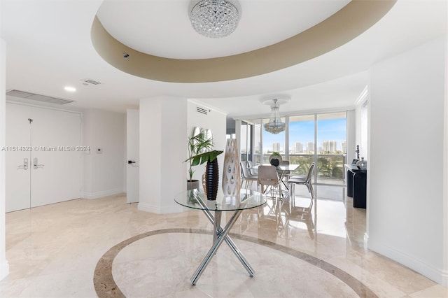 interior space featuring an inviting chandelier, a raised ceiling, light tile patterned floors, and expansive windows